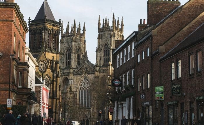 View of York Minster from ground level, the Minster is framed by both side of an adjecent street